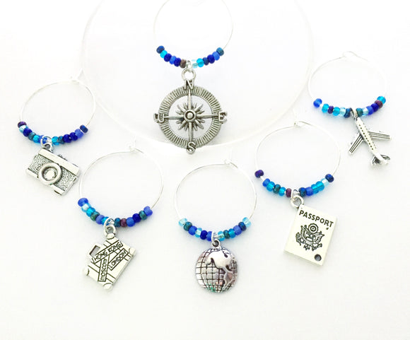 Travel themed Wine Charms: Charms include Camera, Compass, Suitcase, Globe, Passport, and an Airplane. Set of 6 Multi Blue Beaded Charms.